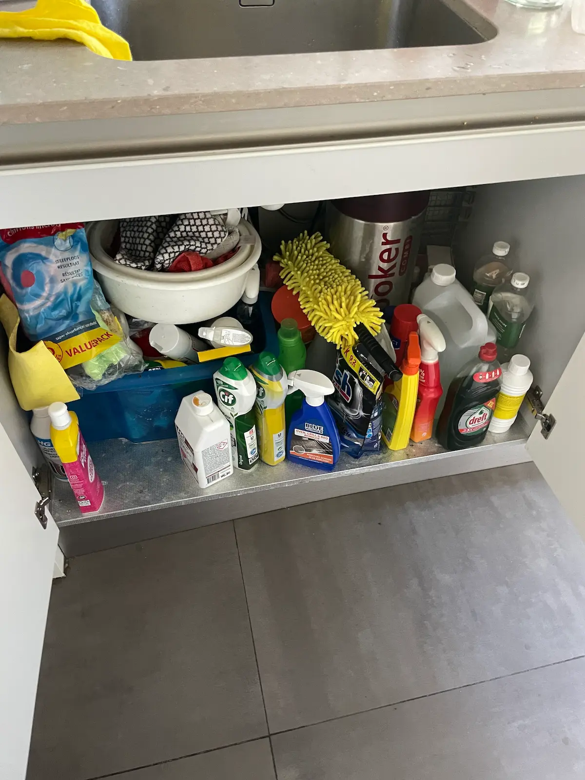 Gootsteenkastje met schoonmaakmiddelen door elkaar, voor het organizen