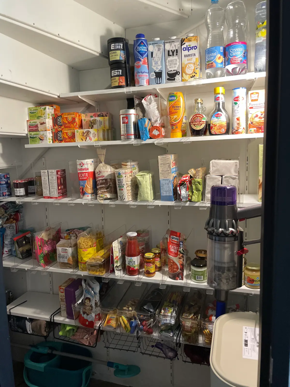 Voorraadkast met voorraadpotten en labels per categorie na organizing